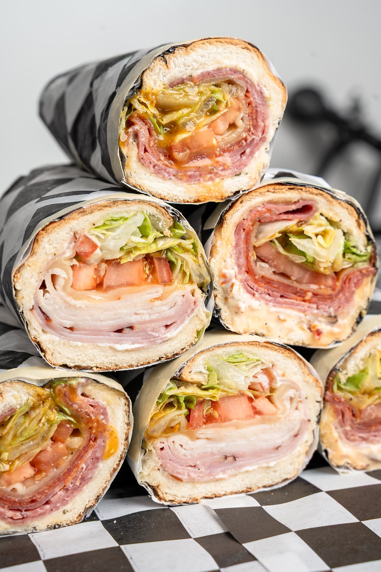 Stack of checkerboard-wrapped submarine sandwiches cut in half