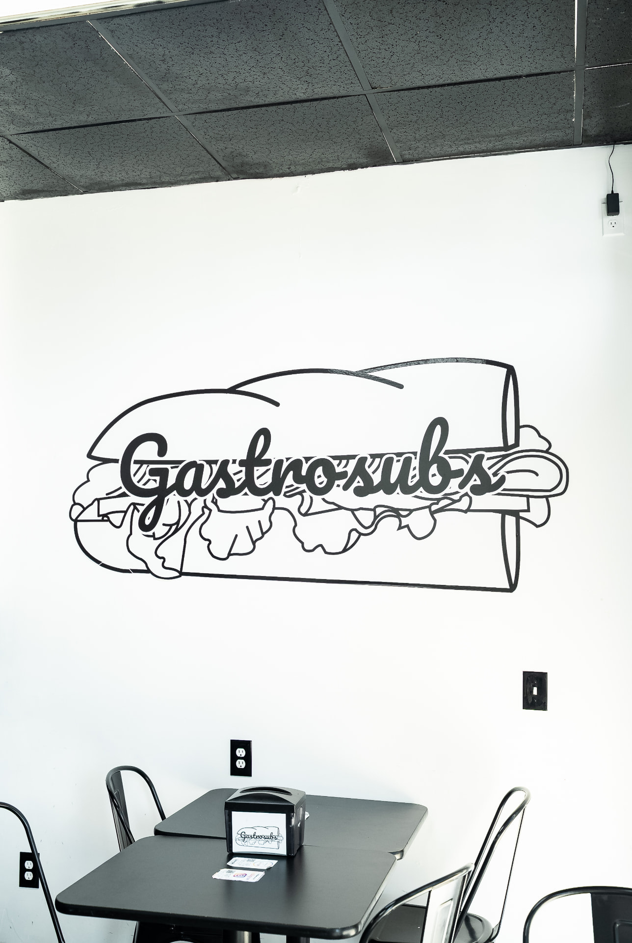 Gastrosubs logo mural painted on a white wall above a dining table